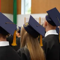 Grupa studentów w togach i biretach podczas uroczystości.